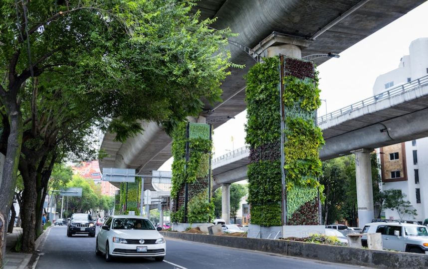 Ambiente urbano con giardini verticali intorno a una strada e con delle macchine di passaggio